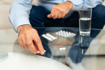 Fototapeta na wymiar Hands with pills. Senior man hands with medical pill and glass of water. Mature old senior grandfather taking medication cure pills vitamin. Age prescription medicine healthcare therapy concept