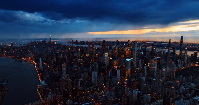 Overcast dark blue sky above the panorama of New York, the USA. Top view of city downtown switching on lights at dusk.