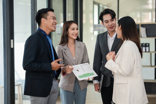 Business colleagues having a casual conversation in the office hallway. Candid workplace interaction. Networking and communication concept - Powered by Adobe