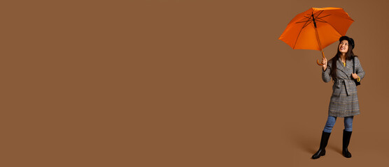 Beautiful young Asian woman with umbrella on brown background