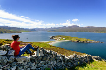 Jeune homme assis sur un muret de pierres  admirant la vue sur la presqu'île Ard Neakie Lime Kilns...