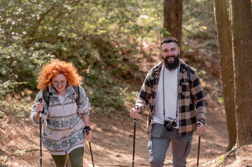 A beautiful and cheerful couple is hiking in the forest enjoying nature and each other's company - 786660934
