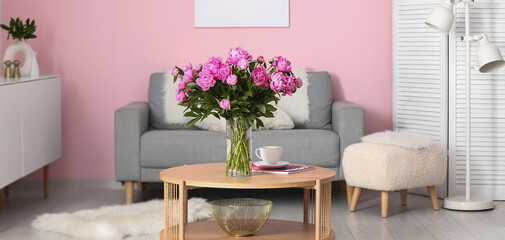 Vase of pink peonies on coffee table with couch in living room
