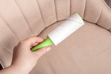 Woman holds sticky roller. Furniture cleaning
