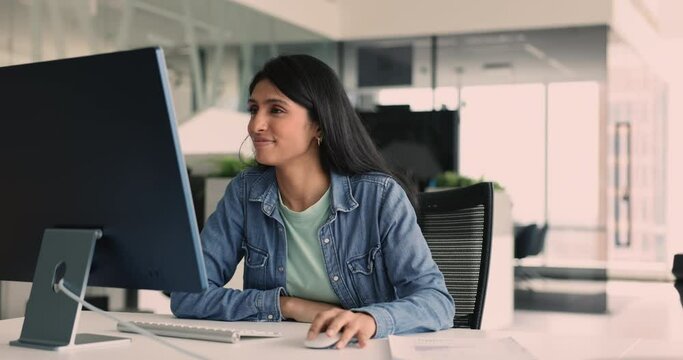 Pretty Indian female office employee working on PC, drafting text based on research and outline, reviewing, revising or formatting text, Communicating with company clients or colleagues by e-mailing