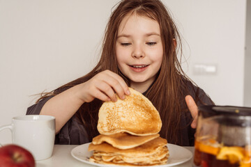 Little cheerful girl is going to eat a stack of pancakes. Happy morning concept. Selected Focus