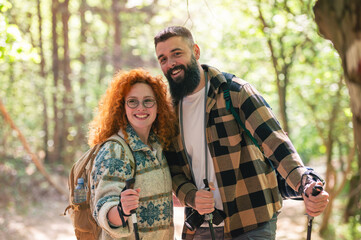 A beautiful and cheerful couple is hiking in the forest enjoying nature and each other's company - 786664309