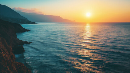 Sunset over ocean with cliffside view, warm tones highlight tranquil seascape. Sun reflection dances on water surface