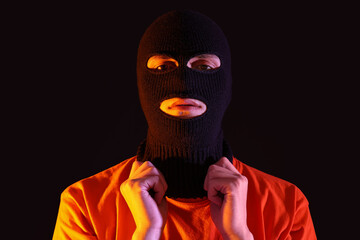 Handsome young man in balaclava on black background