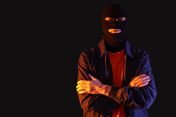 Handsome young man in balaclava on black background