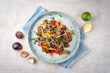 Traditional Asian wok spinach with chestnuts, pepper strips and soy sprouts served as top view in a Nordic design plate with copy space