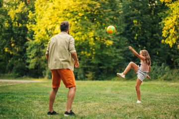 Father and daughter paying ball game in nature.