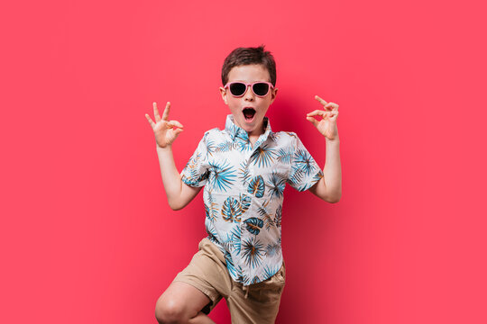 Excited boy in tropical shirt and sunglasses posing