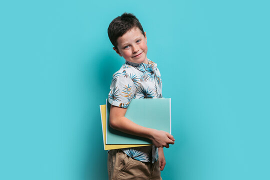 Smiling boy with folders on a turquoise background