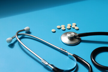 Stethoscope, pills and syringe on blue background, selective focus. Cardiology and healthcare...