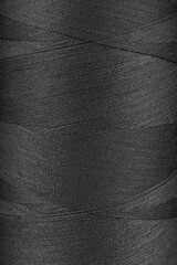 Texture of black color threads in spool close up, macro. Sewing threads bobbin abstract background,...