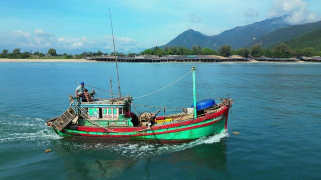 Fishermen Nha Trang in Vietnam are sailing on a against the backdrop of a beautiful landscape and a wonderful mountains on a sunny day. On sunny morning, fishing boat hurries to sea to catch seafood