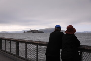 couple on the bridge looking alcatraz island san francisco, usa