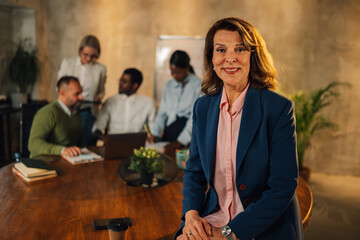 Smiling confident mature businesswoman looking at camera during meeting