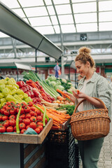 Customer with basket choosing fresh vegetables at farmer's market.