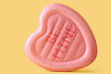 Swimming mattress in shape of heart on yellow background