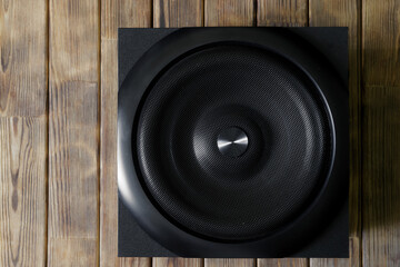 Large and powerful cubic subwoofer in a wooden enclosure with metal grille on a background of...