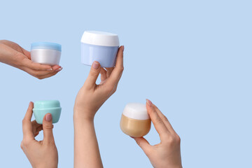 Women with jars of hand cream on blue background