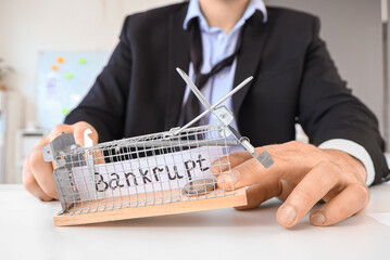 Bankrupt businessman with mousetrap on table in office, closeup