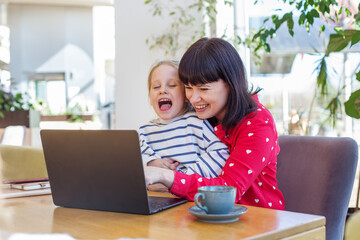 Joyful Mother and Child Laughing at Laptop Screen