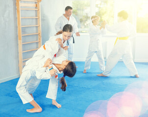 Group of preteen children in kimono practicing karate in a sports gym. Martial arts training session