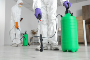 Male workers disinfecting floor in room, closeup