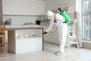 Male worker disinfecting shelf in kitchen