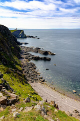 Falaises et plage avec vue au loin du phare Stoer Lighthouse en Ecosse au printemps