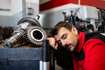 Tired male mechanic sleeping at work.