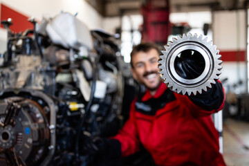 Experienced mechanic or serviceman holding spare parts inside workshop.