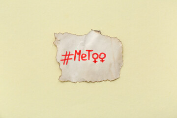 Burnt paper piece with hashtag METOO and gender symbols of woman on yellow background