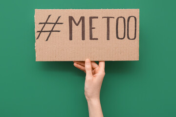 Woman holding cardboard paper with hashtag METOO on green background