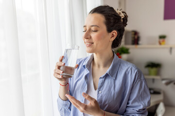 Pretty young woman drinking water and trying to relax and think positive at home