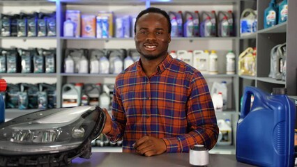 Portrait of african american salesman with automotive headlight in auto parts store. The concept of car repair