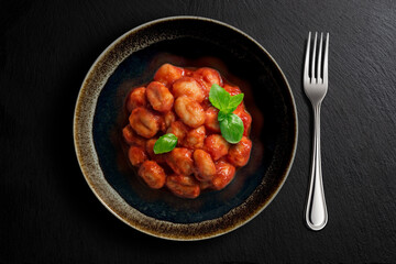 Dark bowl with tomato potato dumpling
