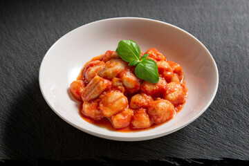 White bowl with tomato potato dumpling