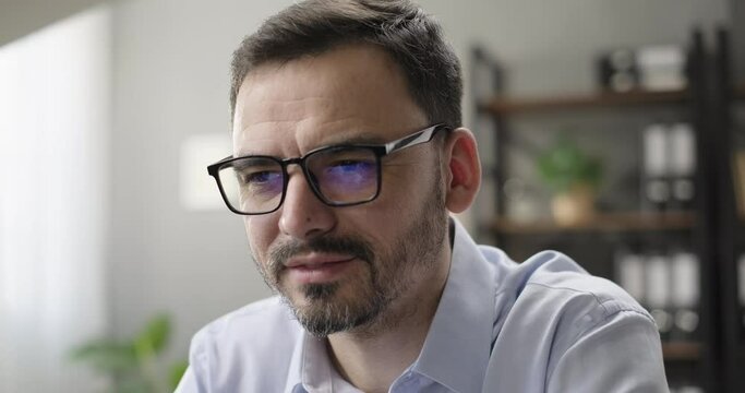 Smiling businessman entrepreneur working online on computer at home desk, laptop screen reflecting in glasses. Successful entrepreneur working on innovation startup, analyzing financial data