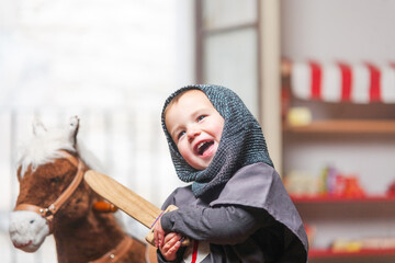 Smiling little boy plays knights with his wooden sword.