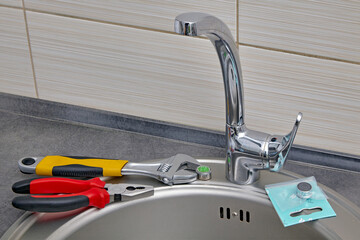 Plumbing tools and faucet aerator prepared for replacement at the edge of the sink