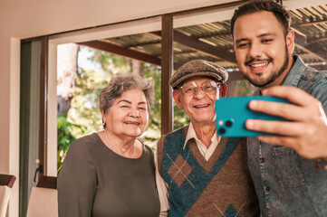 Hispanic Family Making Selfie On Smartphone Posing. Son with his old father and mother.