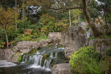 Fototapeta na wymiar Waterfall in Kyoto Garden, a Japanese garden in Holland Park, London, UK. Holland Park is a public park with woods and gardens in the London borough of Kensington.