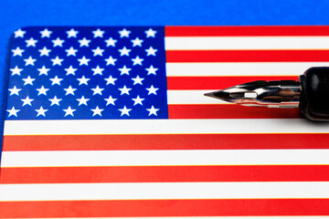 A pen is on top of a red, white and blue American flag