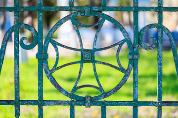 A green metal fence with a design of a circle and a cross