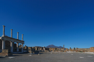 View of Mount Vesuvius through the ruins of the Forum on a sunny day with clear blue sky, Pompeii, Campania, Italy