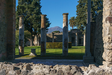 Garden inside ancient luxury house Casa del Fauno in the ruins of Pompei with view through columns at volcano Mount Vesuvius, Pompeii, Campania, Italy